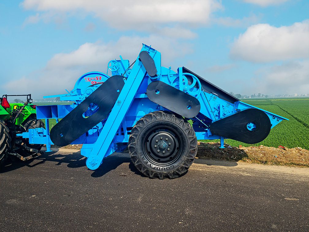 multi crop thresher attached to a tractor in a field.