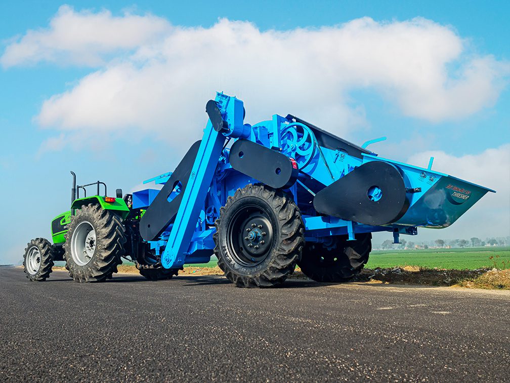 multi-crop thresher attached to a tractor, viewed from the side with a closeup of the front part.