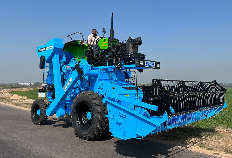 Front view of Punni Tractor Mounted Combine Harvester harvesting wheat in an open field.