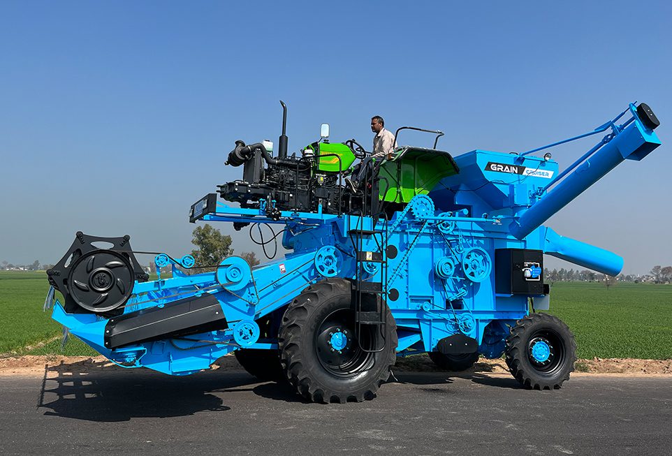 Side profile of tractor-mounted combine harvester with farmer operating in the field.